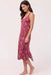 A woman modeling a sleeveless midi-length slip dress with a dusty rose floral print against a plain light background.