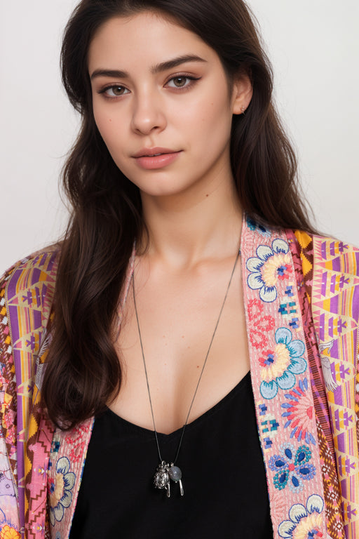 Woman wearing a silver necklace with ladybug and stone charm from Johnny Was
