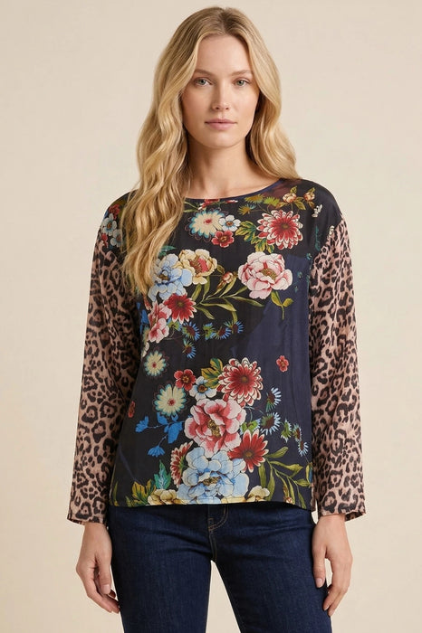Woman wearing a floral top with leopard print sleeves and boat neck from Johnny Was