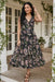 Woman wearing a black floral printed tier midi dress from Johnny Was