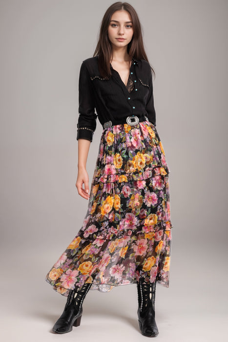Woman wearing a colorful floral silk maxi skirt with tiered ruffles