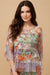 Woman wearing a colorful floral mesh top with ruffle cuffs and hem from Johnny Was