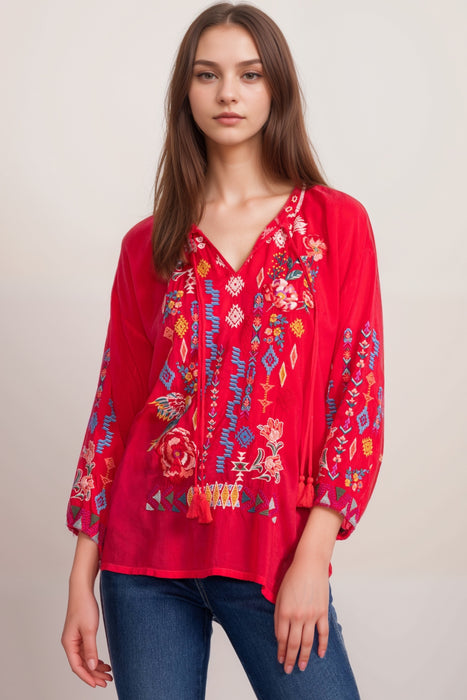 Woman wearing a red blouse with colorful embroidery and 3/4 sleeves