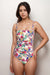 Woman wearing a colorful floral one piece swimsuit with ruching at the front and adjustable straps from Johnny Was