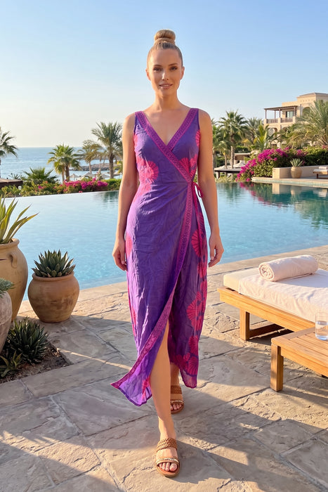 Woman wearing a purple midi wrap dress with pink seashell print and tie waist from Johnny Was