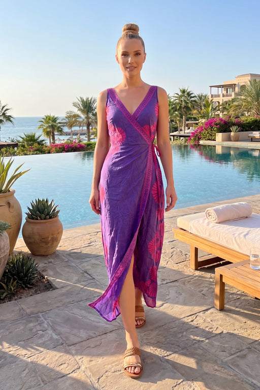 Woman wearing a purple midi wrap dress with pink seashell print and tie waist from Johnny Was