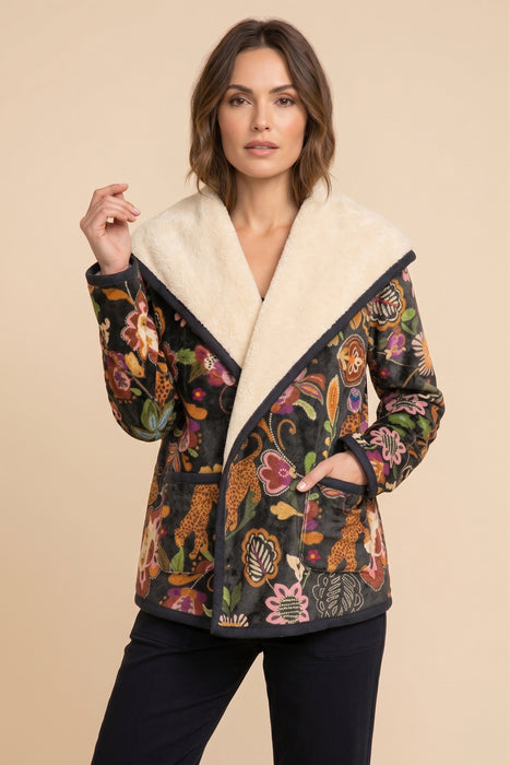 A woman models a long-sleeve jacket featuring a cream-colored sherpa collar and a dark multicolor floral and paisley patterned body, set against a solid beige background.