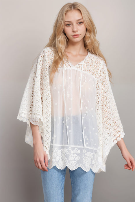 Woman wearing a white embroidered top with lace yoke and sleeves from Johnny Was