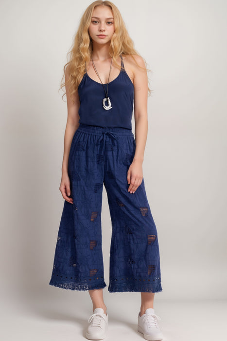 Woman wearing a blue embroidered cropped pant with fringe hem and cutouts