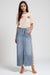 Woman wearing a medium wash denim skirt with front slit and crochet side seams from Johnny Was