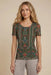 Woman wearing green short sleeve mesh tee with colorful floral and geometric patterns from Johnny Was