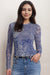 Woman wearing a blue mesh top with denim lace print and long sleeves