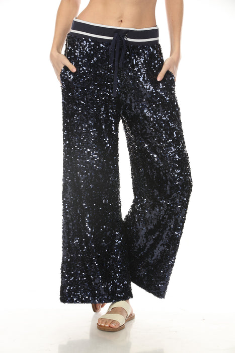 Woman wearing navy sequined wide leg pants with striped waistband and side pockets from Johnny Was