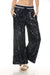 Woman wearing navy sequined wide leg pants with striped waistband and side pockets from Johnny Was