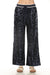 Woman wearing navy sequined wide leg pants with striped waistband and side pockets from Johnny Was