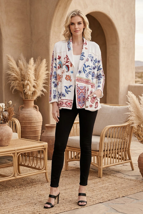 Woman wearing a white open front jacket with colorful embroideries and side pockets from Johnny Was
