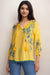 Woman wearing a yellow floral embroidered top v-neck tassel tie