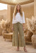 Woman wearing a green wide leg embroidered pants with smocked waist from Johnny Was