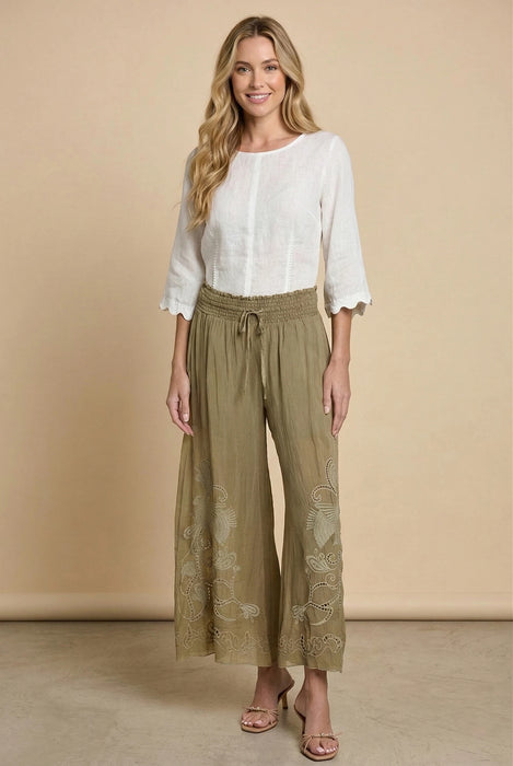 Woman wearing a green wide leg embroidered pants with smocked waist from Johnny Was