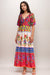 Woman wearing a colorful floral-printed maxi dress with v-neck and puff sleeves from Johnny Was