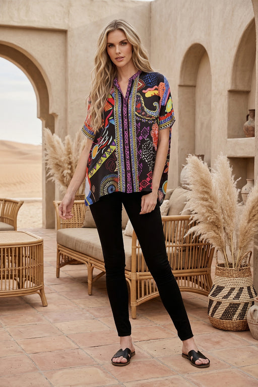 Woman wearing a colorful patterned button down shirt with short sleeves from Johnny Was