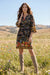 Woman wearing a black shift dress with colorful floral and paisley pattern from Johnny Was