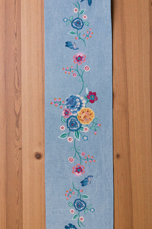Floral embroidered denim blue table runner on a wooden surface