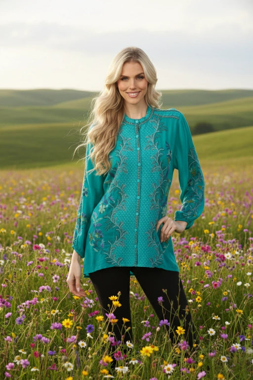 Woman wearing a teal embroidered blouse with button down front and puff sleeves from Johnny Was