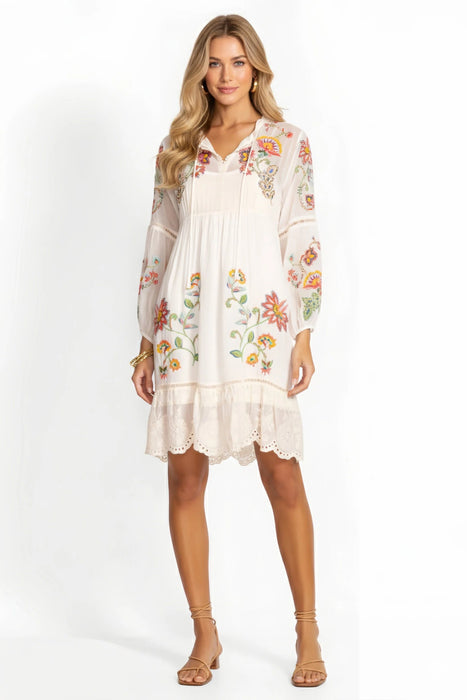 Woman wearing a white dress with floral embroidery and split v-neck with tie fromt Johnny Was
