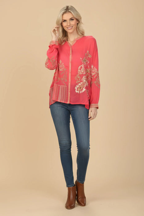 Woman wearing a coral long sleeve blouse with floral embroidery and button front from Johnny Was