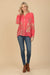Woman wearing a coral long sleeve blouse with floral embroidery and button front from Johnny Was