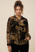 Woman wearing a black floral patterned semi-sheer shirt with long sleeves from Johnny Was
