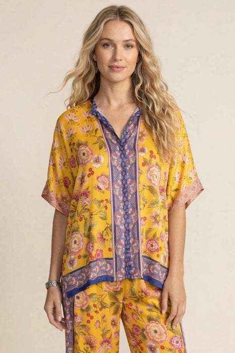 Woman wearing a yellow floral-printed short sleeve tunic top with button front and mandarin collar from Johnny Was