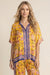 Woman wearing a yellow floral-printed short sleeve tunic top with button front and mandarin collar from Johnny Was