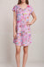 Woman wearing a pink sleep dress with florals and travel post stamps from Johnny Was