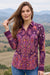 A woman wearing a purple long-sleeve button-up shirt with a colorful paisley and floral pattern from Johnny Was