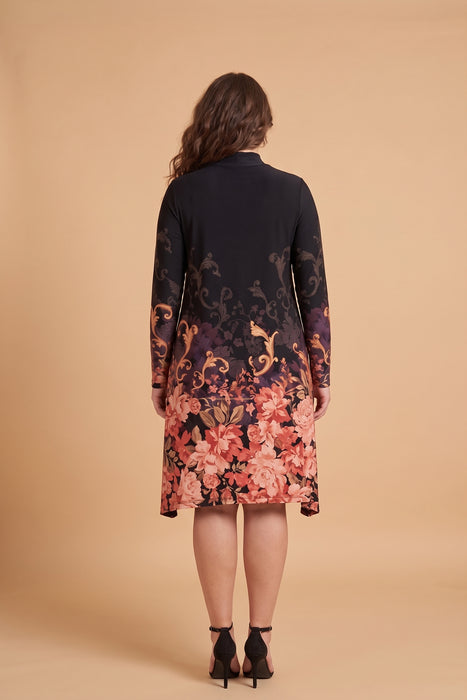 A woman viewed from the back wearing a long-sleeve knee-length dress with a dark navy upper section and a vibrant floral gradient pattern transitioning into pink, red, and orange tones near the hem, set against a solid beige studio background.