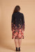 A woman viewed from the back wearing a long-sleeve knee-length dress with a dark navy upper section and a vibrant floral gradient pattern transitioning into pink, red, and orange tones near the hem, set against a solid beige studio background.