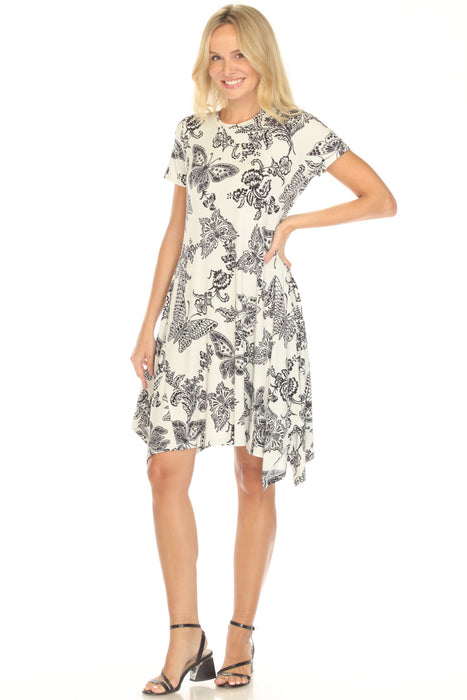 Woman wearing a white dress with butterfly print and handkerchief hem from Johnny Was