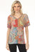 Woman wearing a colorful mosaic tile patterned tee with v-neck and short sleeves from Johnny Was