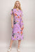 Woman wearing a purple midi dress with colorful florals and side tie detail from Johnny Was