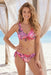 Woman wearing a pink floral printed low rise bottom with decorative side ties from Johnny Was