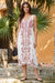 A woman stands outdoors wearing a sleeveless white midi dress with embroidery from Johnny Was