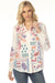 Woman wearing a white button down shirt with colorful embroideries from Johnny Was