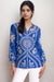 Woman wearing a blue embroidered blouse with intricate patterns and button front from Johnny Was