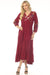 Woman wearing a burgundy dress with floral embroidery and tiered maxi skirt from Johnny Was