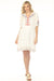 Woman wearing a white dress with tonal plaid and vibrant geometric embroidery from Johnny Was
