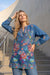 Woman wearing a blue floral printed tunic top with v-neck and long sleeves from Johnny Was