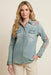 Woman wearing a blue denim shirt with geometric embroidery and chest pockets from Johnny Was