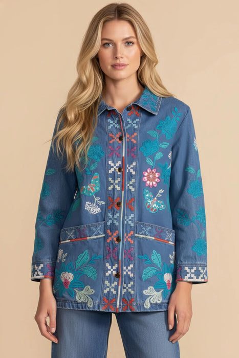 Woman wearing a blue denim jacket with colorful floral and geometric embroideries from Johnny Was